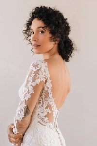 Close-up of a long sleeve lace wedding dress showcasing sheer floral sleeves, an open-back design, and detailed lace patterns for a sophisticated bridal finish.