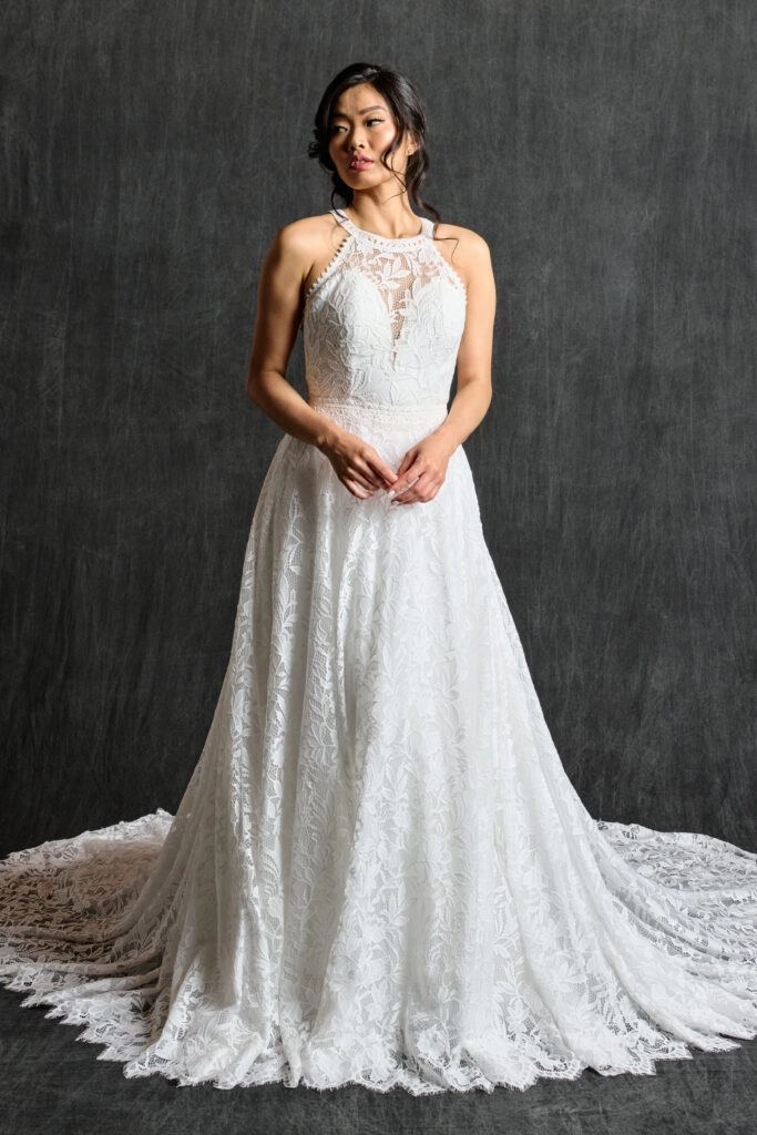 Front view of a halter neck lace wedding dress featuring a high neckline and delicate floral lace pattern, complemented by a flowing skirt and soft train, ideal for a modern yet timeless bridal look.