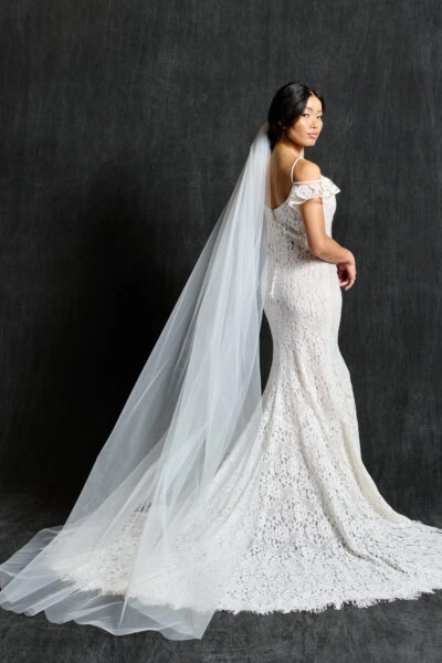 Bride wearing a chapel length tulle wedding veil, showcasing its elegant flow and raw-edge design, paired with a lace wedding dress.