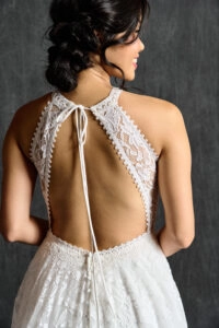 Close-up of the back of a halter neck lace wedding dress, showcasing an intricate open-back design with floral lace details and a delicate tie closure, adding elegance to the bridal look.