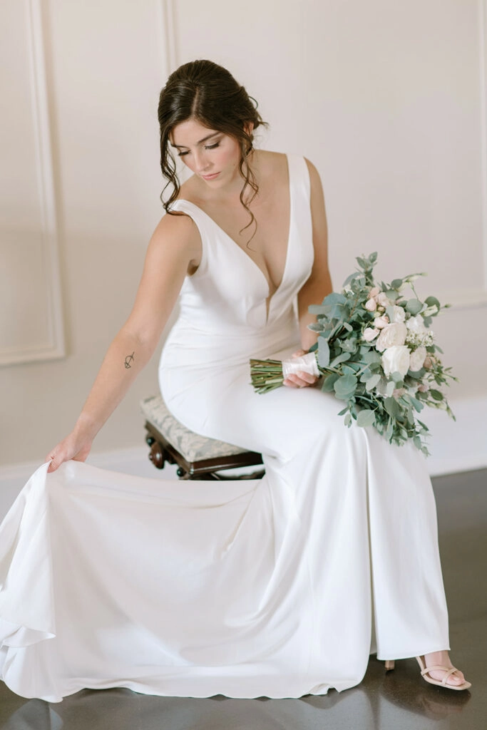 classic crepe bridal gown deep v neck romantic updo bride sitting with bouquets